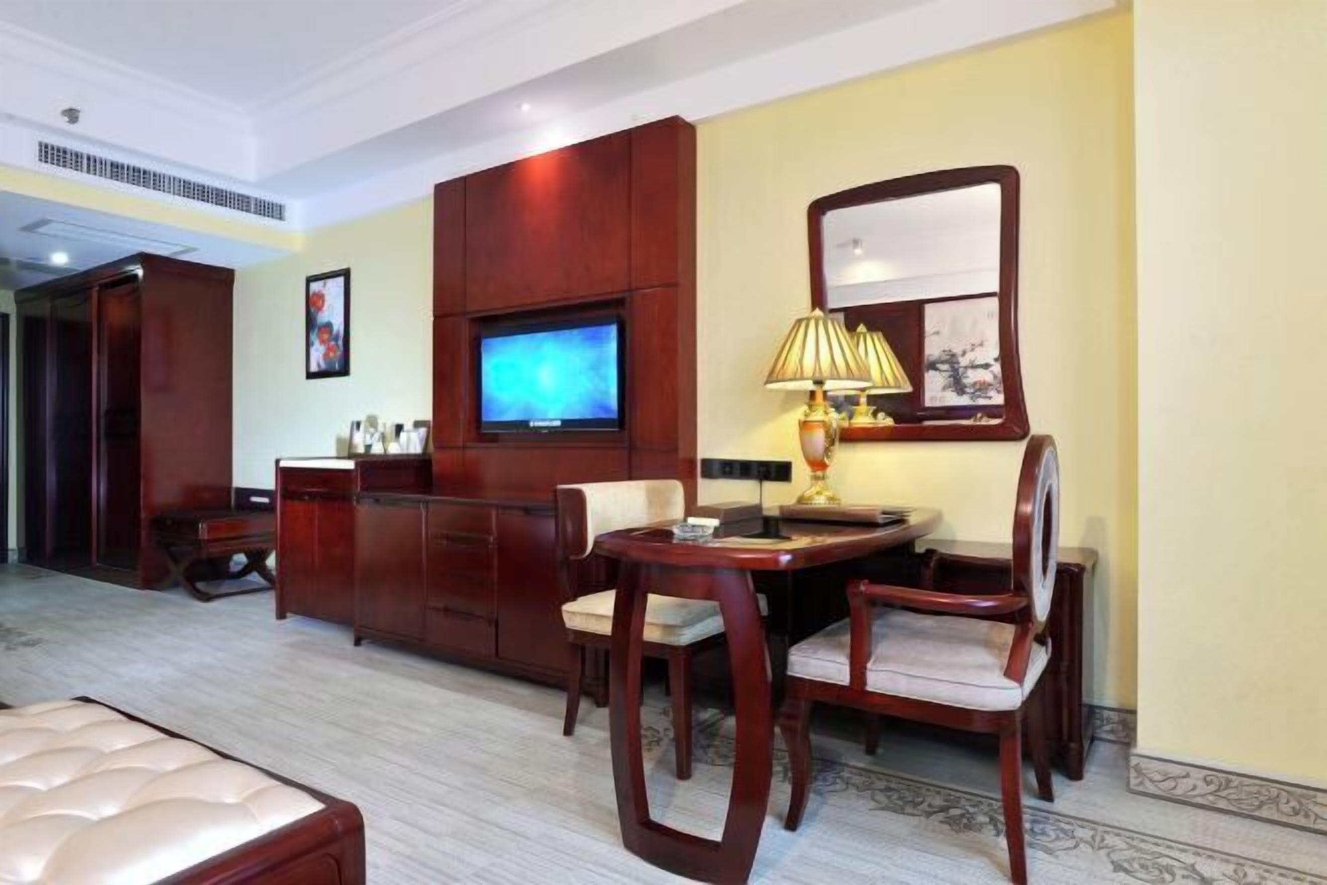 Une chambre d’hôtel avec un lit, une télévision, un bureau avec une lampe et une chaise.