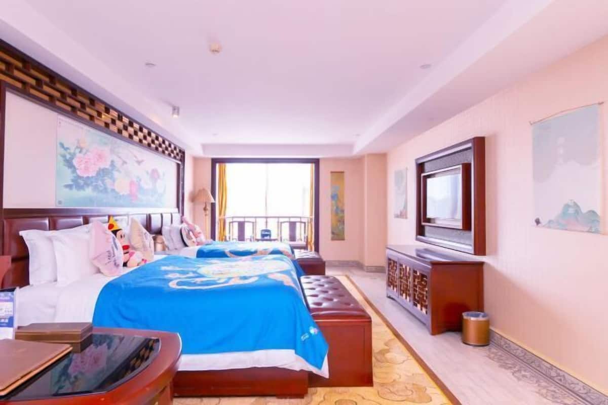 A hotel room with a large bed, a TV, a desk, and a balcony.