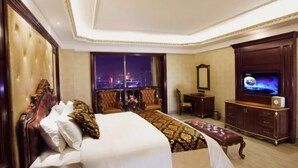 A hotel room with a large bed, a television, a desk, and a view of the city at night. - Wanjiali International Hotel (Changsha)