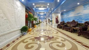 A hotel lobby with a long corridor, ornate wall carvings, a patterned floor, and seating areas with plush sofas. - Wanjiali International Hotel (Changsha)