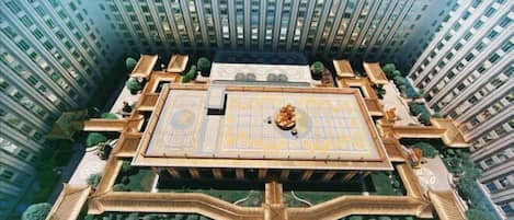 A high-rise building with a central courtyard featuring a large, ornate fountain and surrounding greenery.