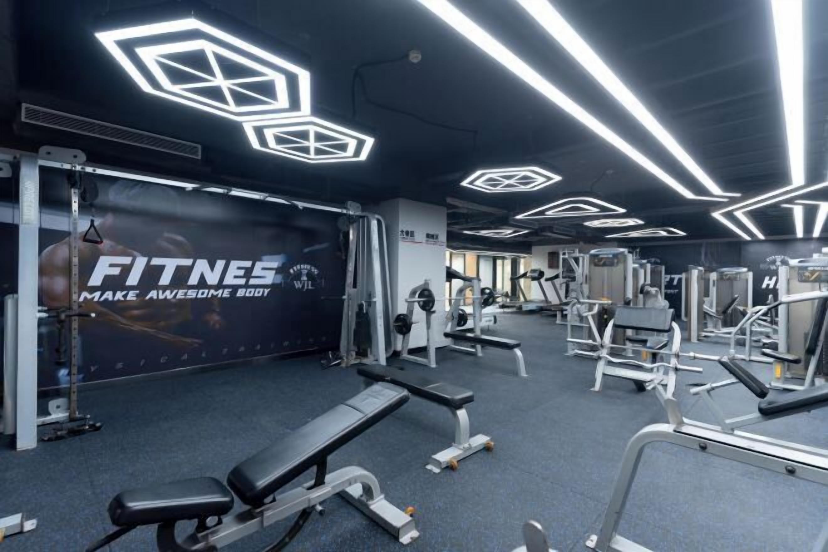 Une salle de sport équipée de divers appareils d’exercice, dotée d’un grand miroir et affichant des affiches motivantes.
