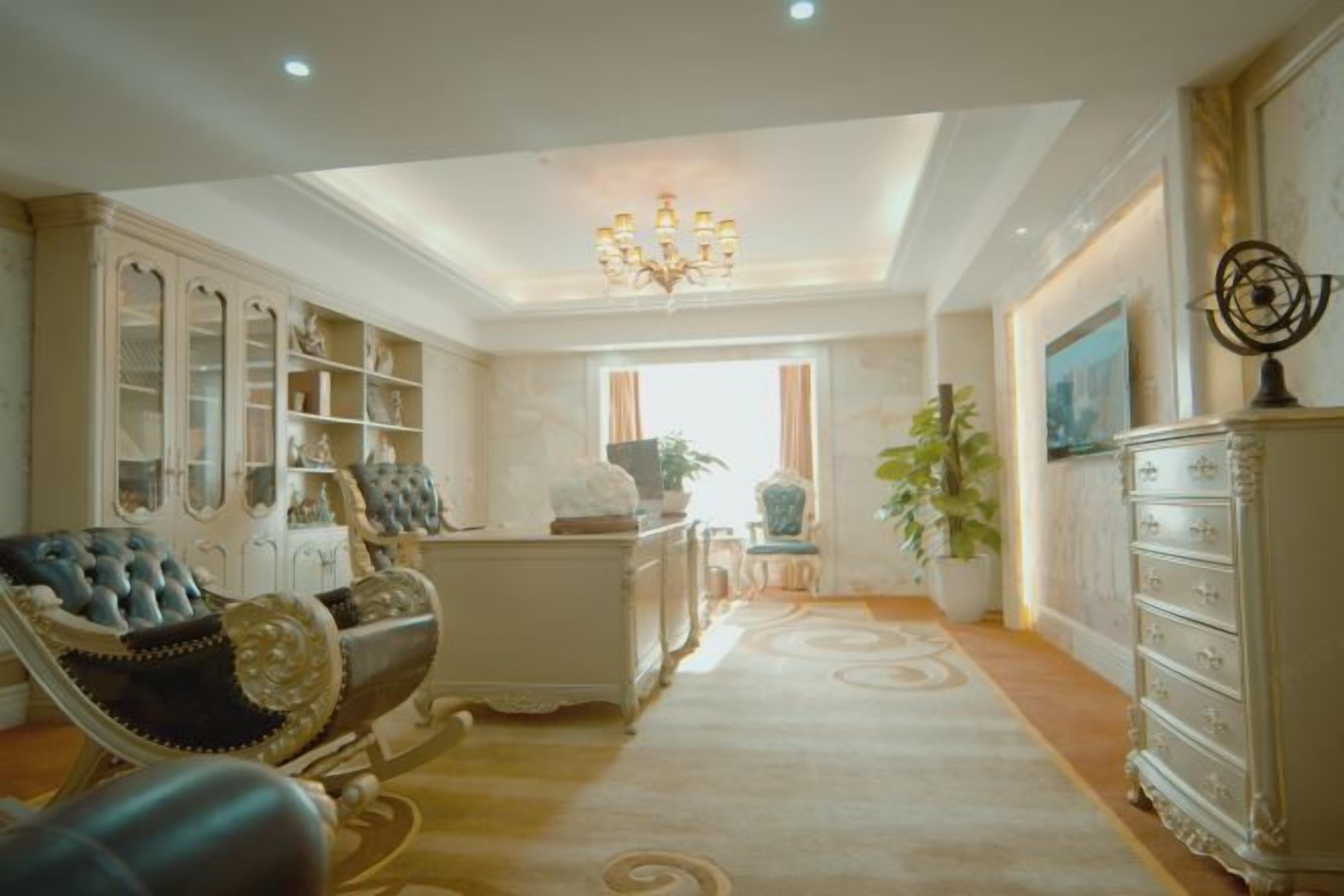 Una habitación amplia con candelabro, un sillón grande, un aparador con puertas de cristal y una planta en maceta.