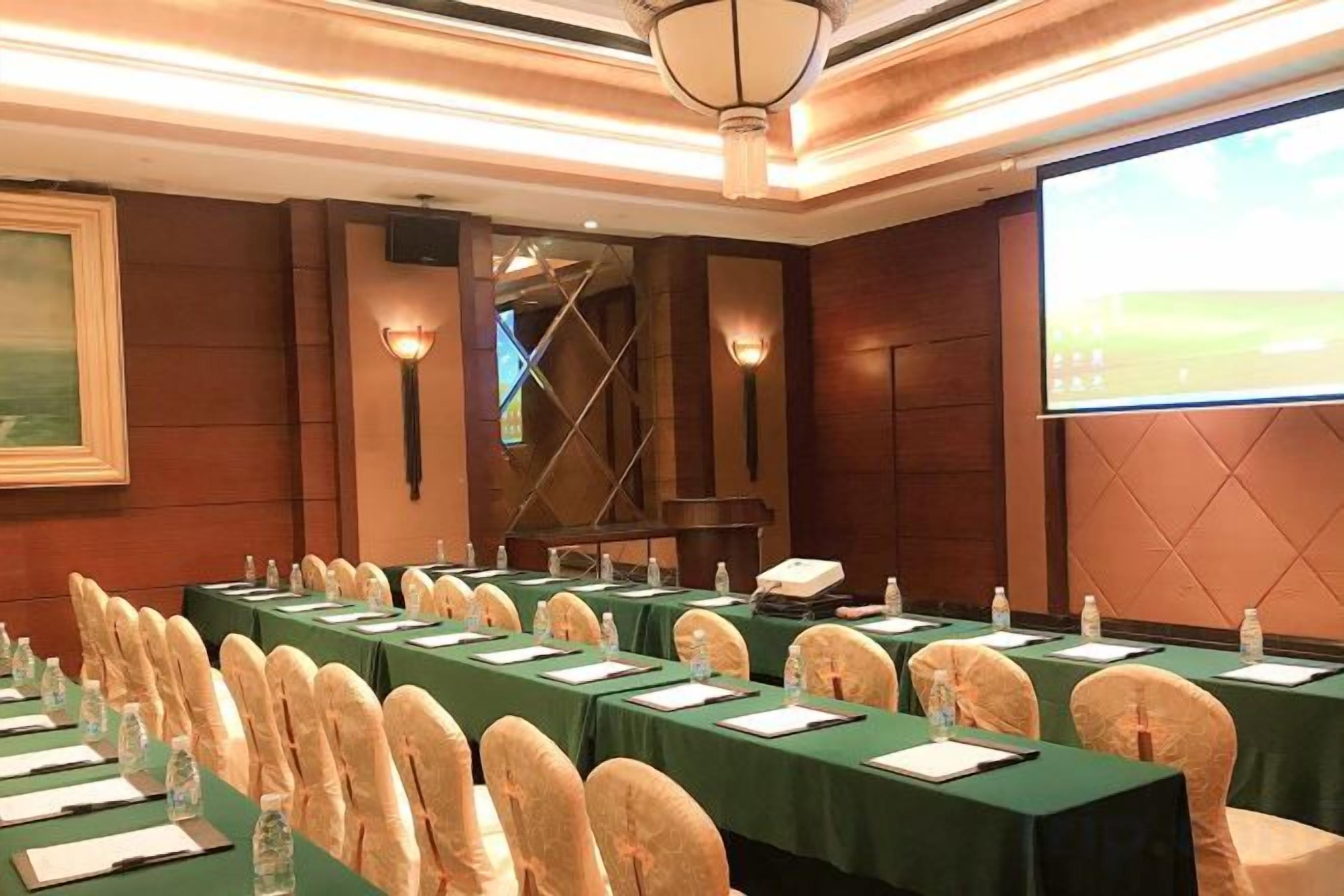 A conference room with long tables, chairs, and a projector screen.