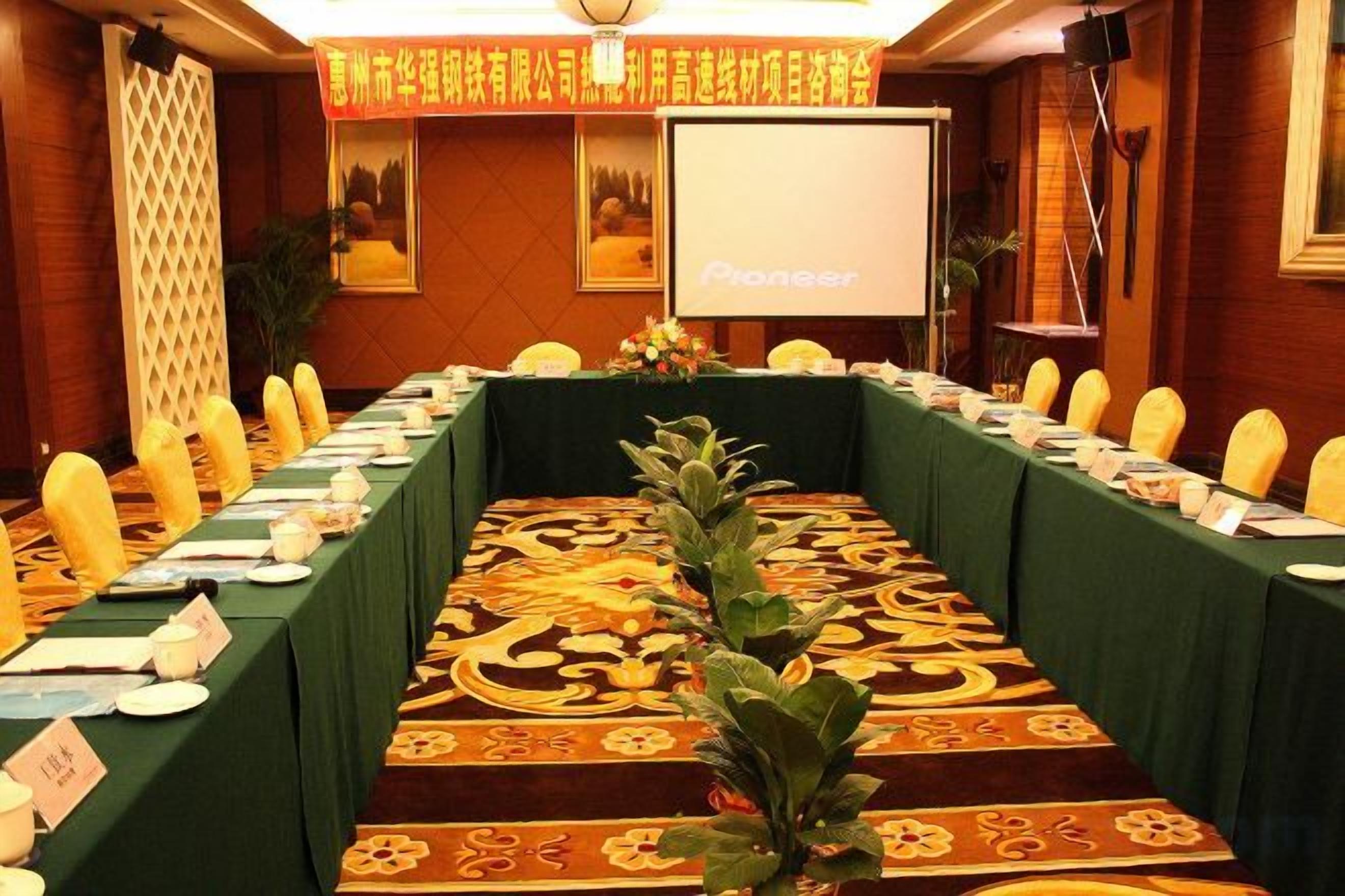 A conference room with a long table, chairs, and a projector screen.
