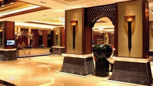 Una hall con reception, pilastri decorativi e un’ampia scultura sferica.