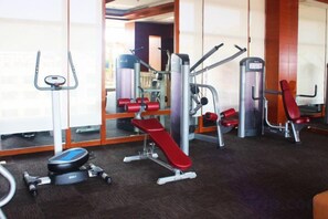 A gym with various exercise equipment, including a bench press, a squat rack, and a cable machine. - Gophoe Hotel (Huizhou City)