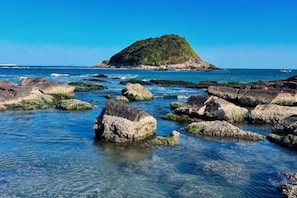Un paisaje costero con aguas claras, rocas y una pequeña isla.