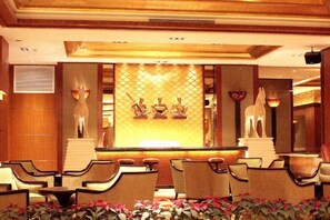 A reception area with a reception desk, chairs, and decorative wall art. - Gophoe Hotel (Huizhou City)