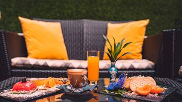 A breakfast setting with a beverage, a fruit plate, and a dessert on a table.