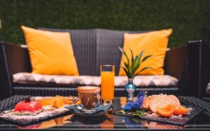 A breakfast setting with a beverage, a fruit plate, and a dessert on a table.