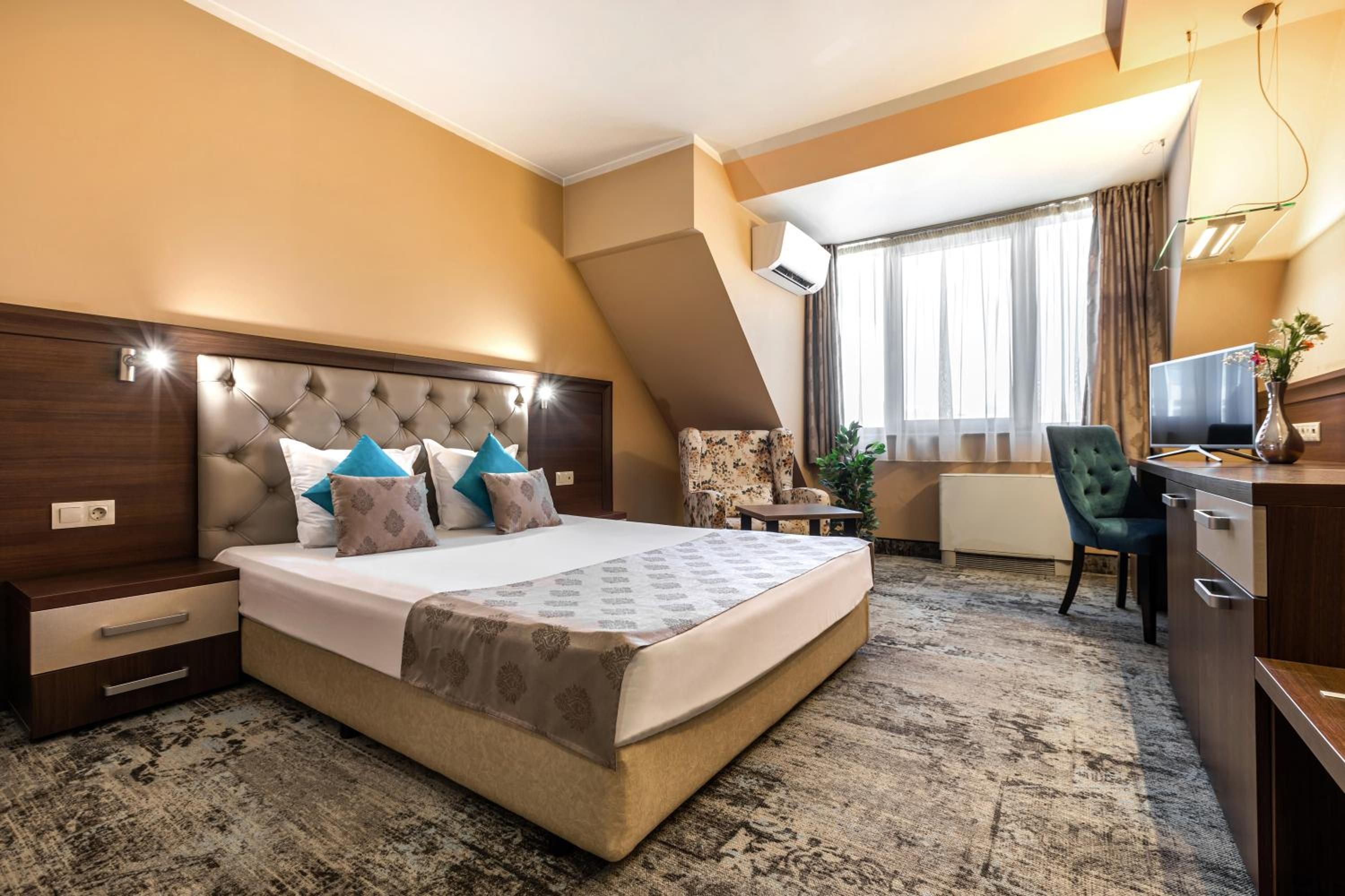 A hotel room with a large bed, a desk, a chair, and a television.
