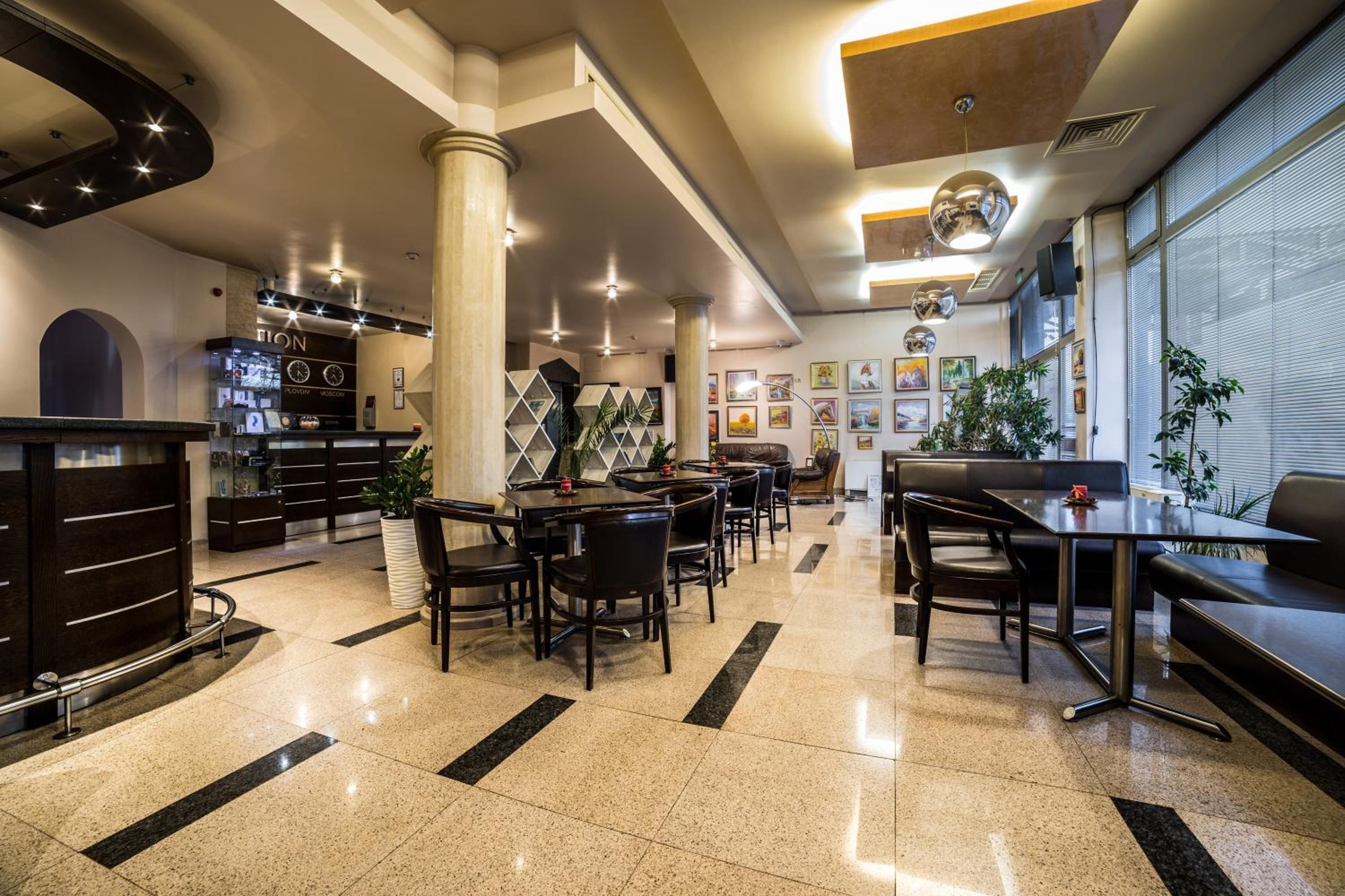 A modern hotel lobby with a reception desk, seating area, and artwork on the walls.