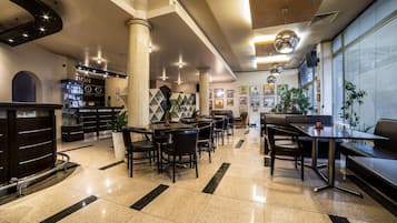 A modern hotel lobby with a reception desk, seating area, and artwork on the walls.