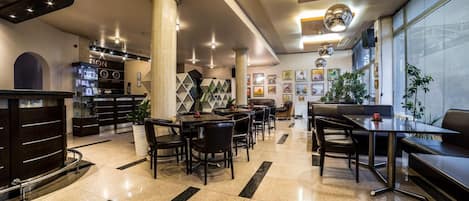 Un moderno vestíbulo de hotel con mostrador de recepción, zona de estar y obras de arte en las paredes.