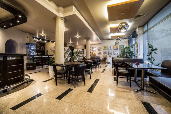 A modern hotel lobby with a reception desk, seating area, and artwork on the walls.