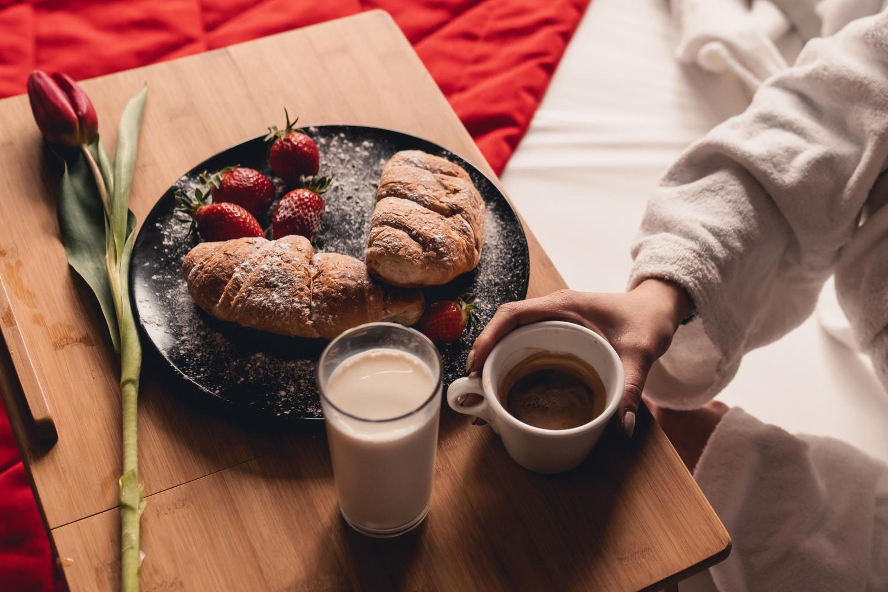 Una bandeja de desayuno con pasteles, fresas y un vaso de leche sobre una mesa de madera.