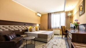A hotel room with a large bed, a sofa, a desk, and a chair. - Business Hotel Plovdiv (Plovdiv)