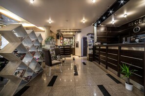 A reception area with a modern design, including a reception desk, seating area, and a unique geometric bookshelf. - Business Hotel Plovdiv (Plovdiv)