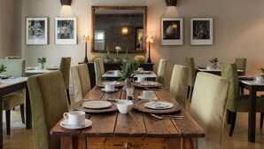 A dining area with a wooden table set for six, surrounded by green upholstered chairs. - Welgelegen Boutique Hotel (Gardens)
