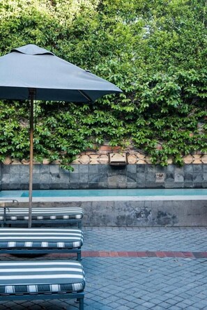 A poolside area with lounge chairs and a large umbrella.