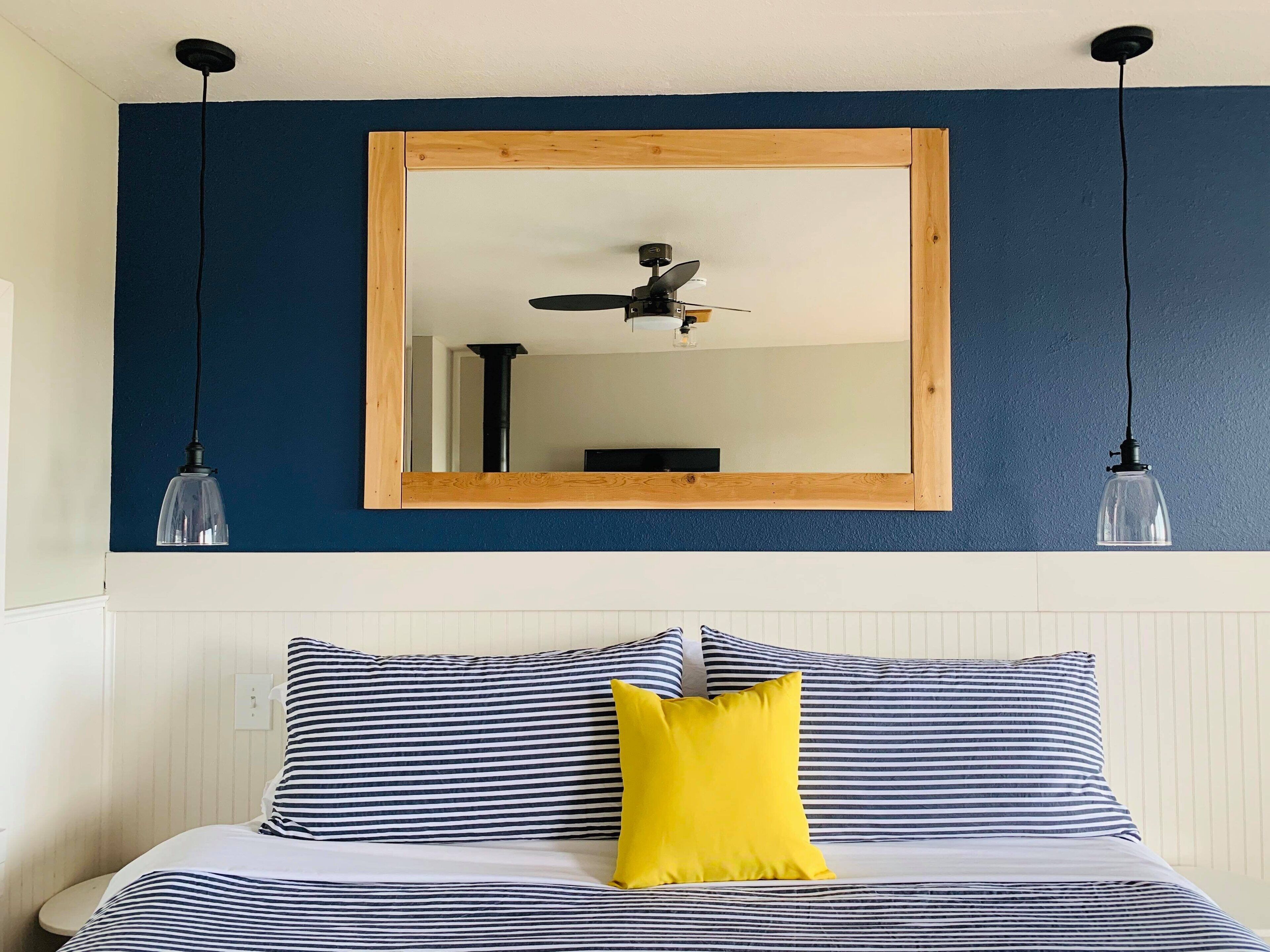 A bedroom with a bed, a mirror, and two pendant lights.