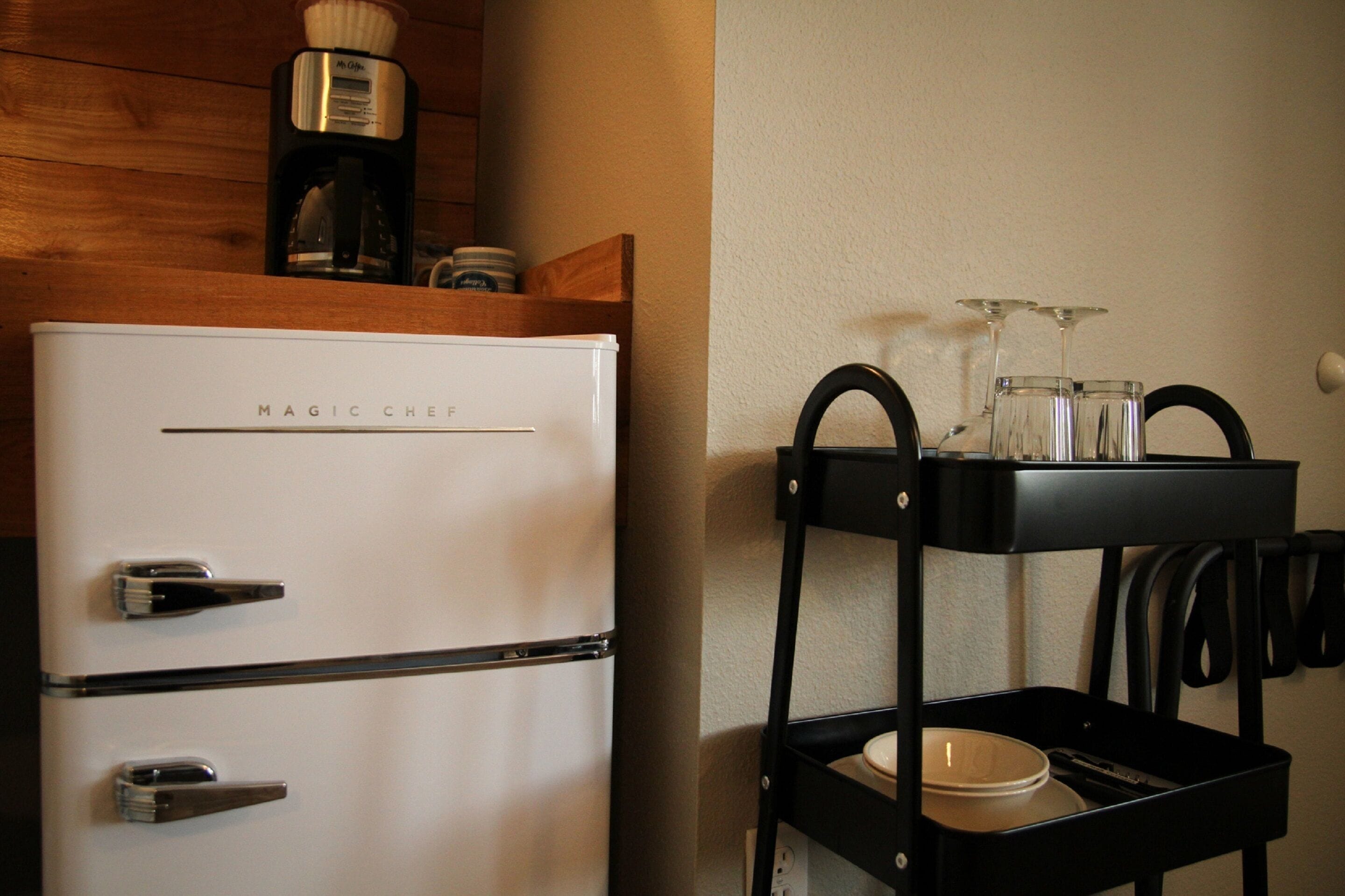 A kitchen with a white MAGIC CHEF refrigerator, a coffee maker, and a black utensil holder with glasses.