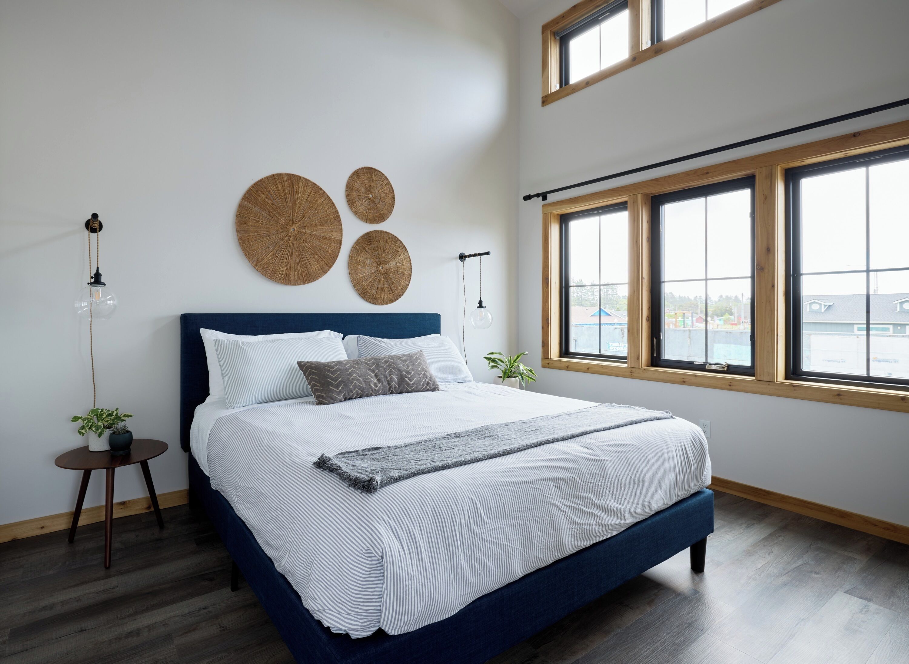 Camera da letto moderna con un letto grande, due lampade a parete e vista all'esterno tramite ampie finestre.