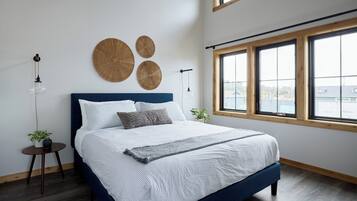 Camera da letto moderna con un letto grande, due lampade a parete e vista all'esterno tramite ampie finestre.