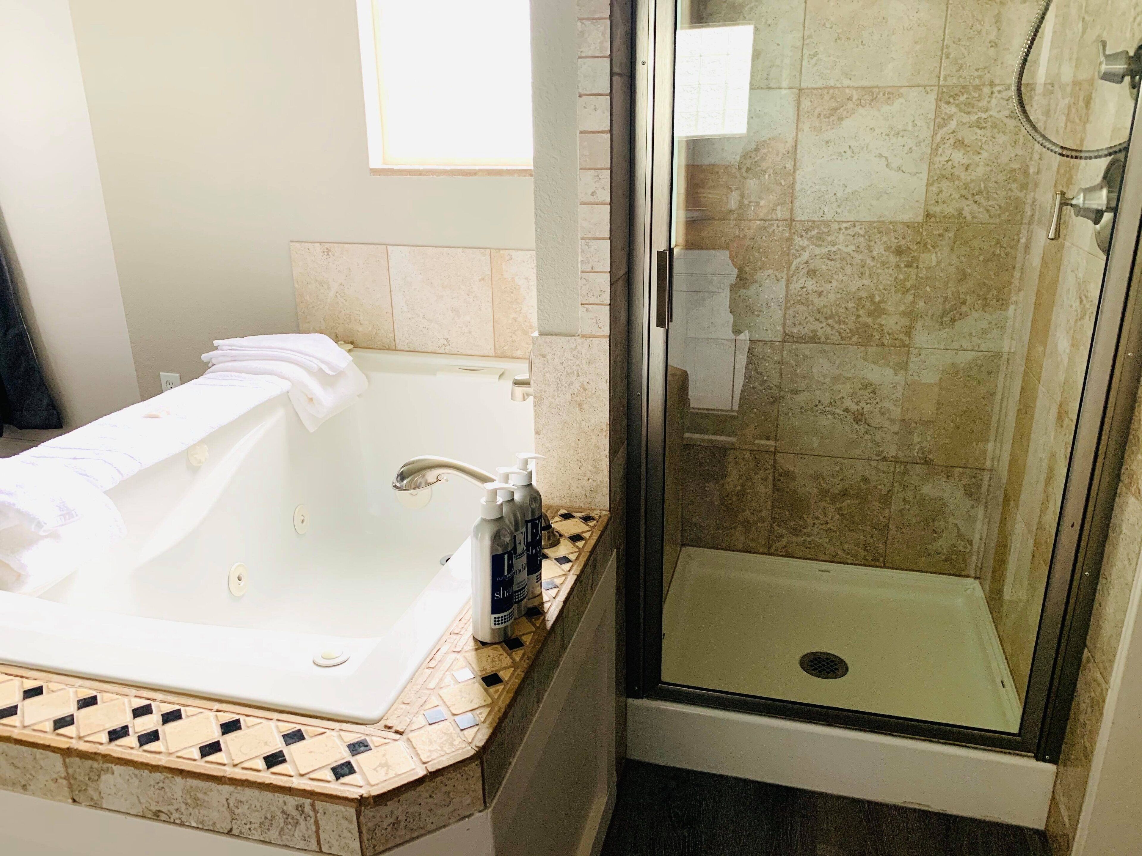 Un baño con bañera, ducha y suelo de baldosas.