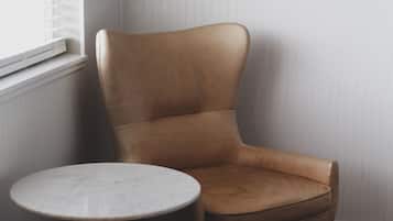 Een kamer met een bruine leren fauteuil, een klein rond tafeltje en een ronde poef.