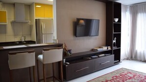 Una cocina moderna con refrigerador integrado, un televisor de pantalla plana grande montado en la pared y una zona de bar con taburetes.