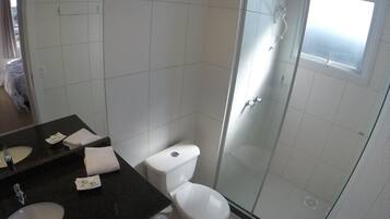 A bathroom with a white toilet, a glass-enclosed shower, and a black countertop with a sink and mirror.