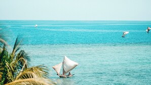 Una vista despejada de un mar tranquilo con un velero y una persona en el agua.