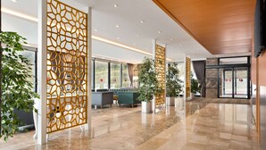 Un vestíbulo espacioso con piso de mármol pulido, mobiliario moderno y paneles de madera decorativos.