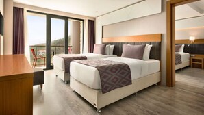 Habitación de hotel con dos camas, un escritorio y un balcón con una silla.