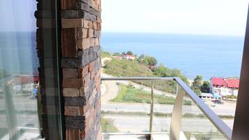 A view from a balcony overlooking a coastal road with a clear blue sea in the background.