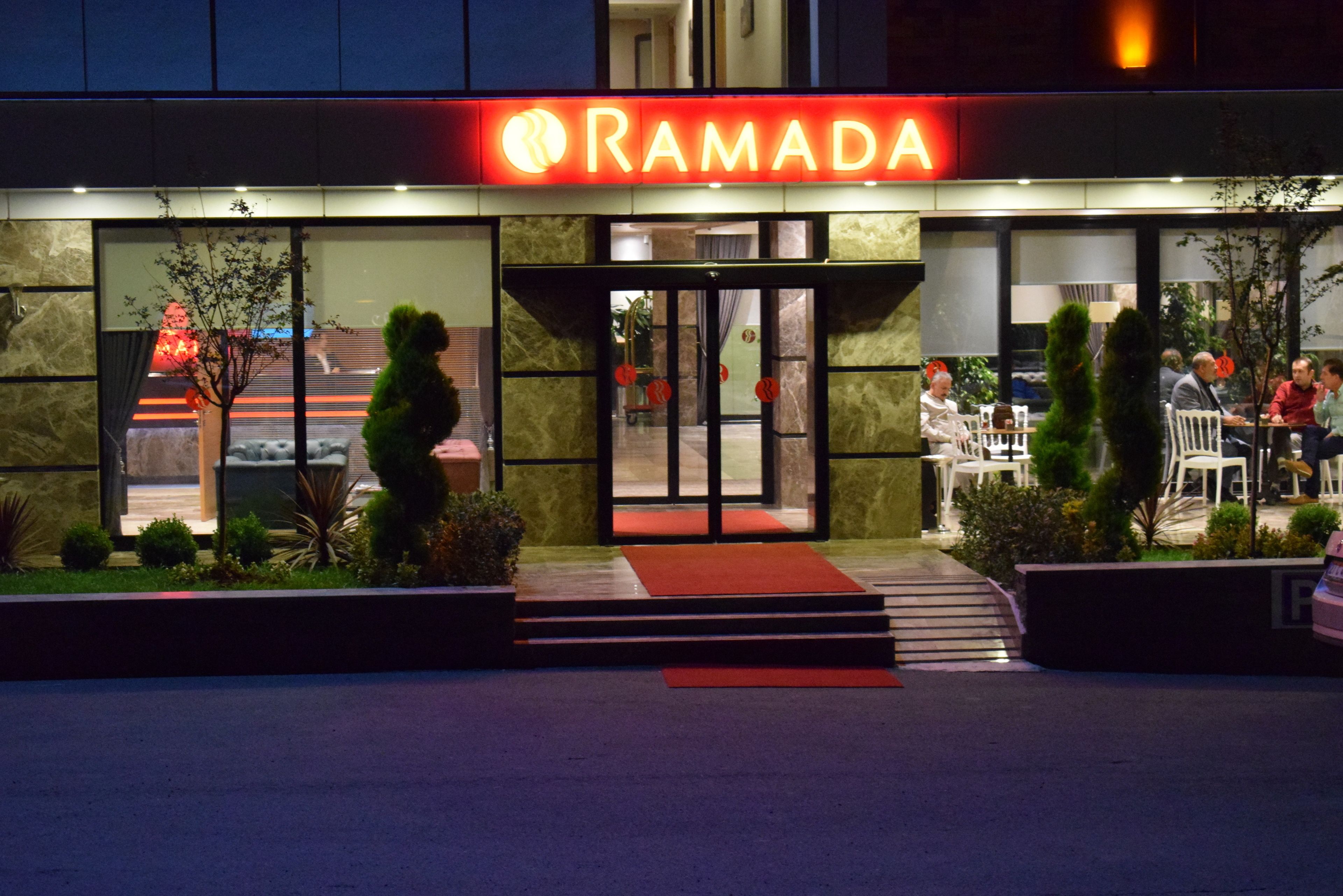 A restaurant named Ramada with outdoor seating and a red awning.