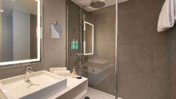 A modern bathroom with a large mirror, a sink, and a shower area.