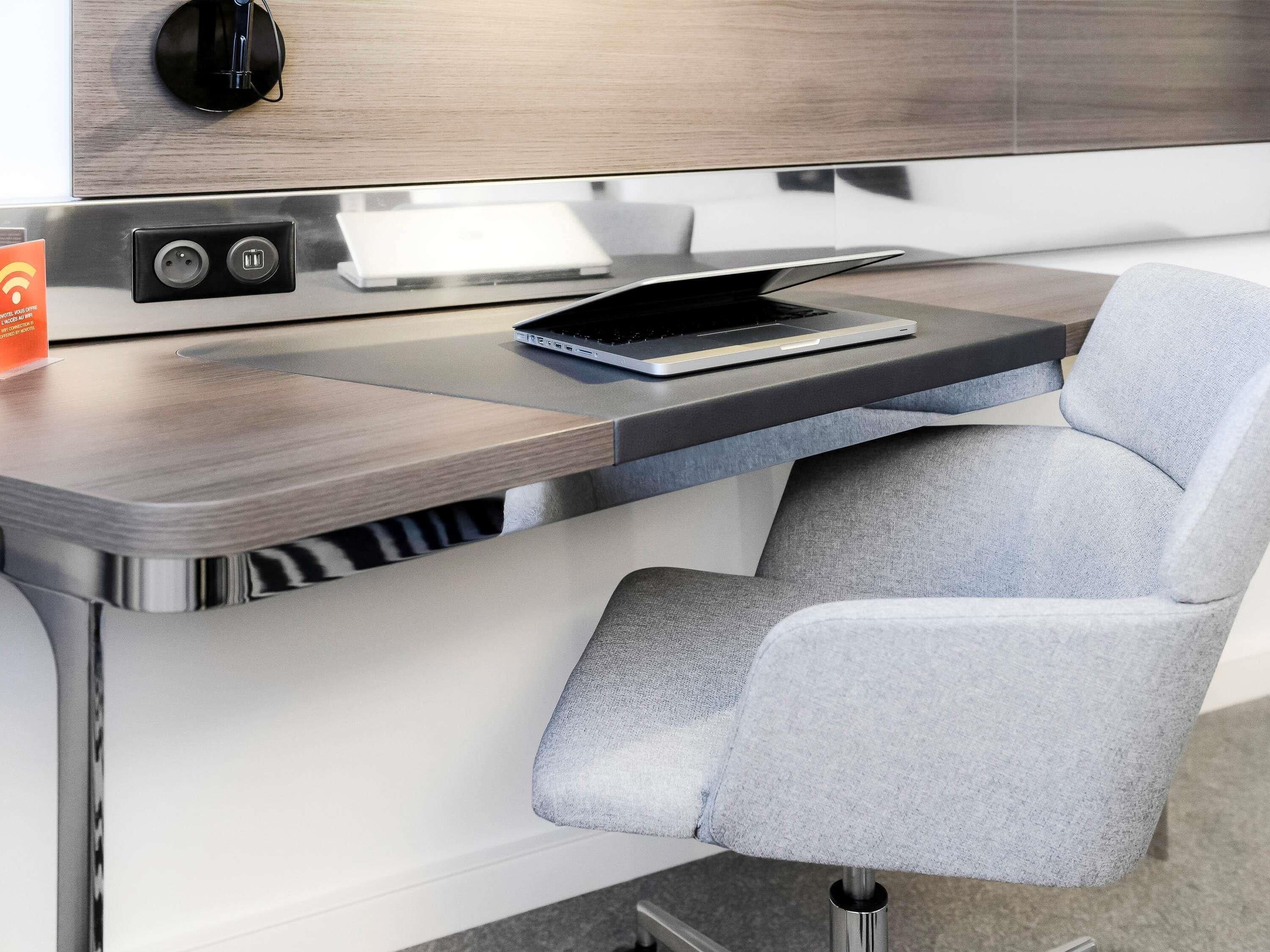 A modern, compact workspace with a laptop, a power outlet, and a charging cable.