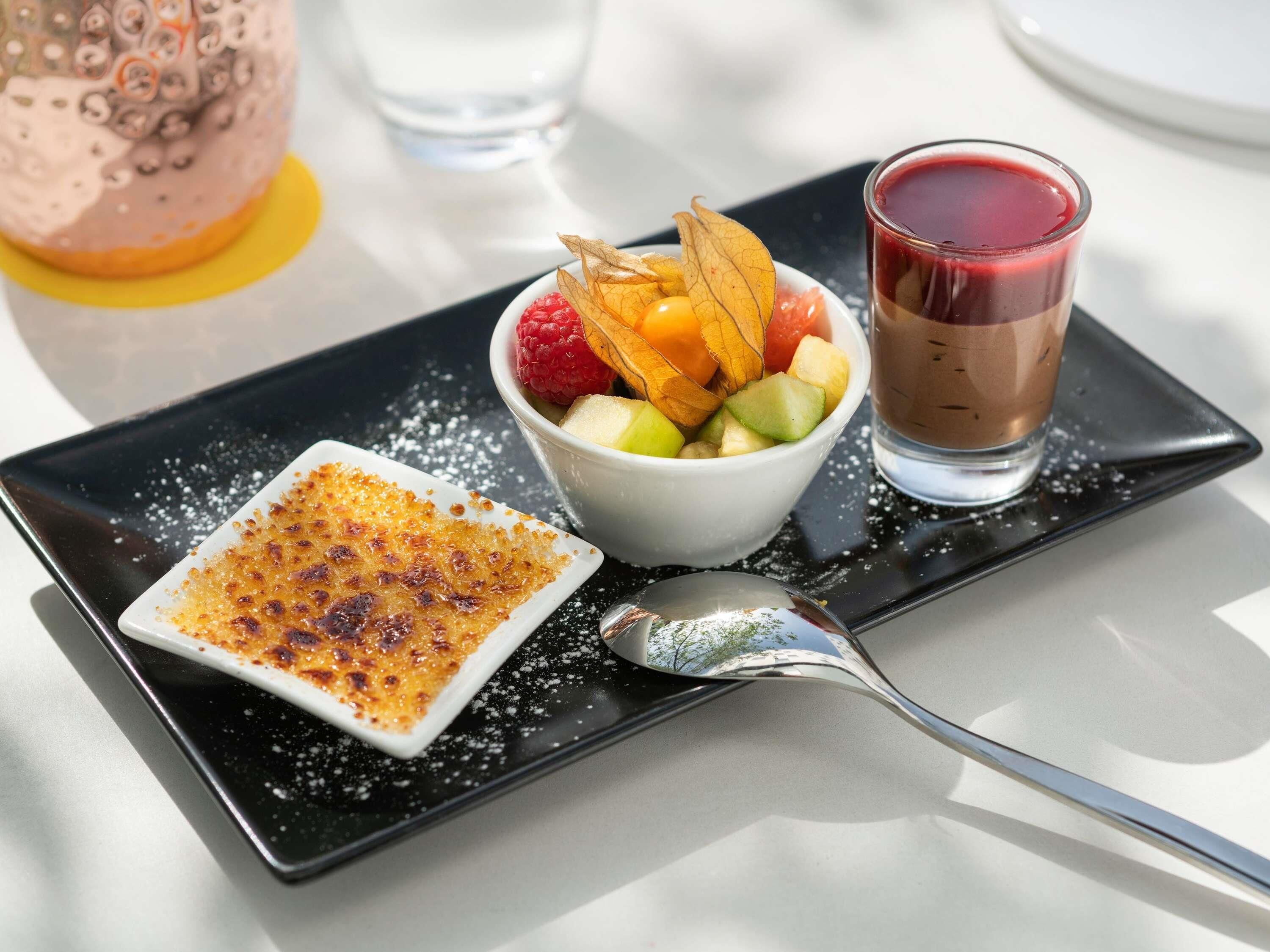 En desserttallerken med crème brûlée, frugtsalat og en chokoladedrik.