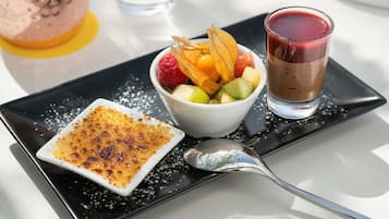 En desserttallerken med crème brûlée, frugtsalat og en chokoladedrik.