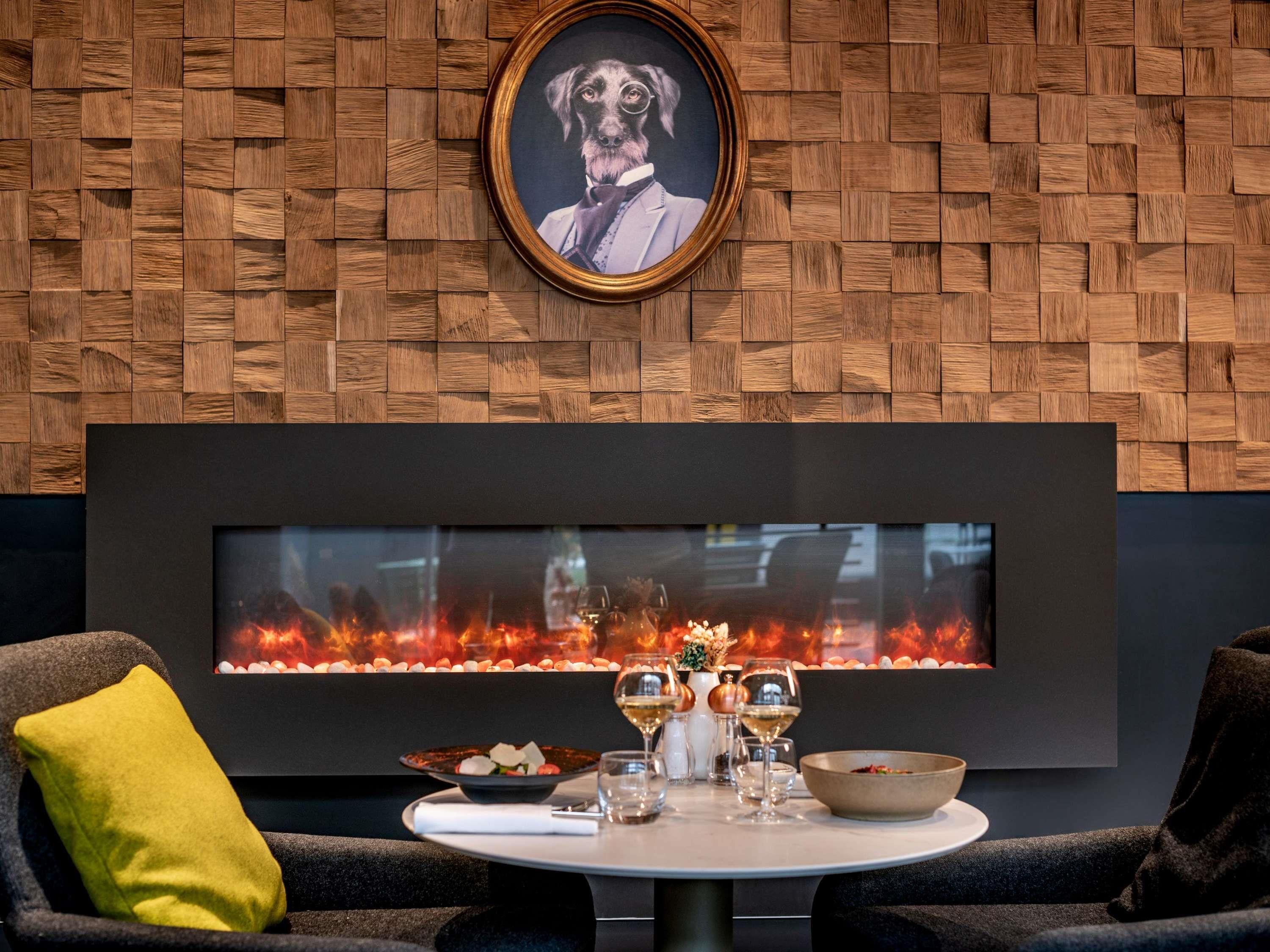 Ein modernes Interieur mit einer Holzwand, einem gerahmten Bild, einem Kamin und einer Esszeile.
