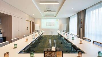 A conference room with a long table, chairs, a projector screen, and a presentation.