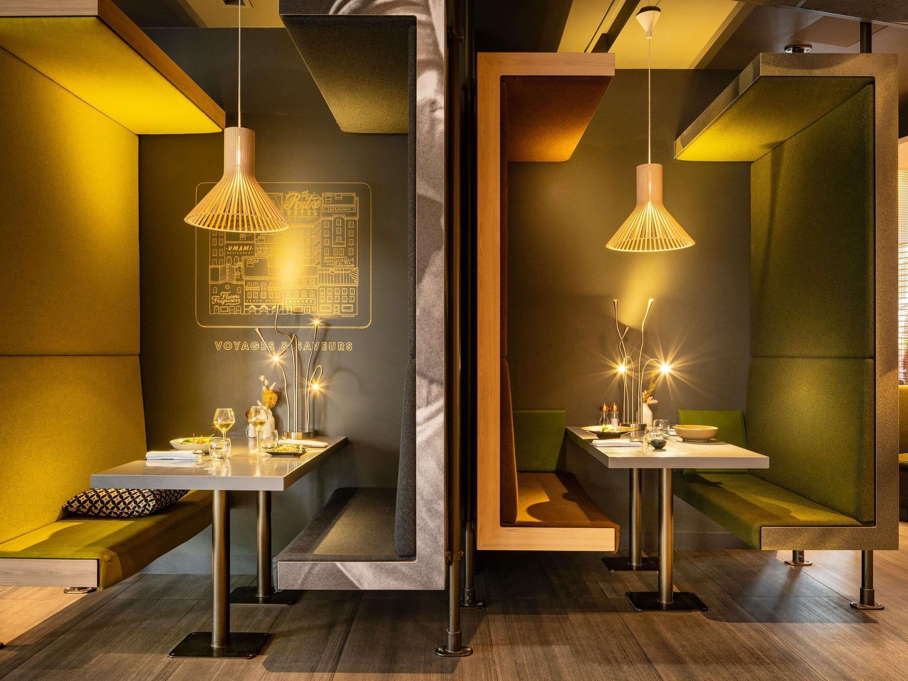 A modern dining area with tables, chairs, and pendant lighting.