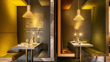 A modern dining area with tables, chairs, and pendant lighting.
