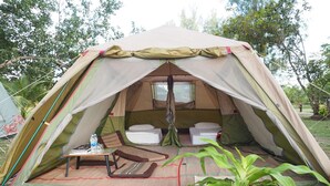 Uma tenda com área de dormir, uma mesinha e uma garrafa de água.