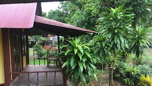 Eine Holzhütte mit Balkon, umgeben von üppigem Grün und einem Garten.
