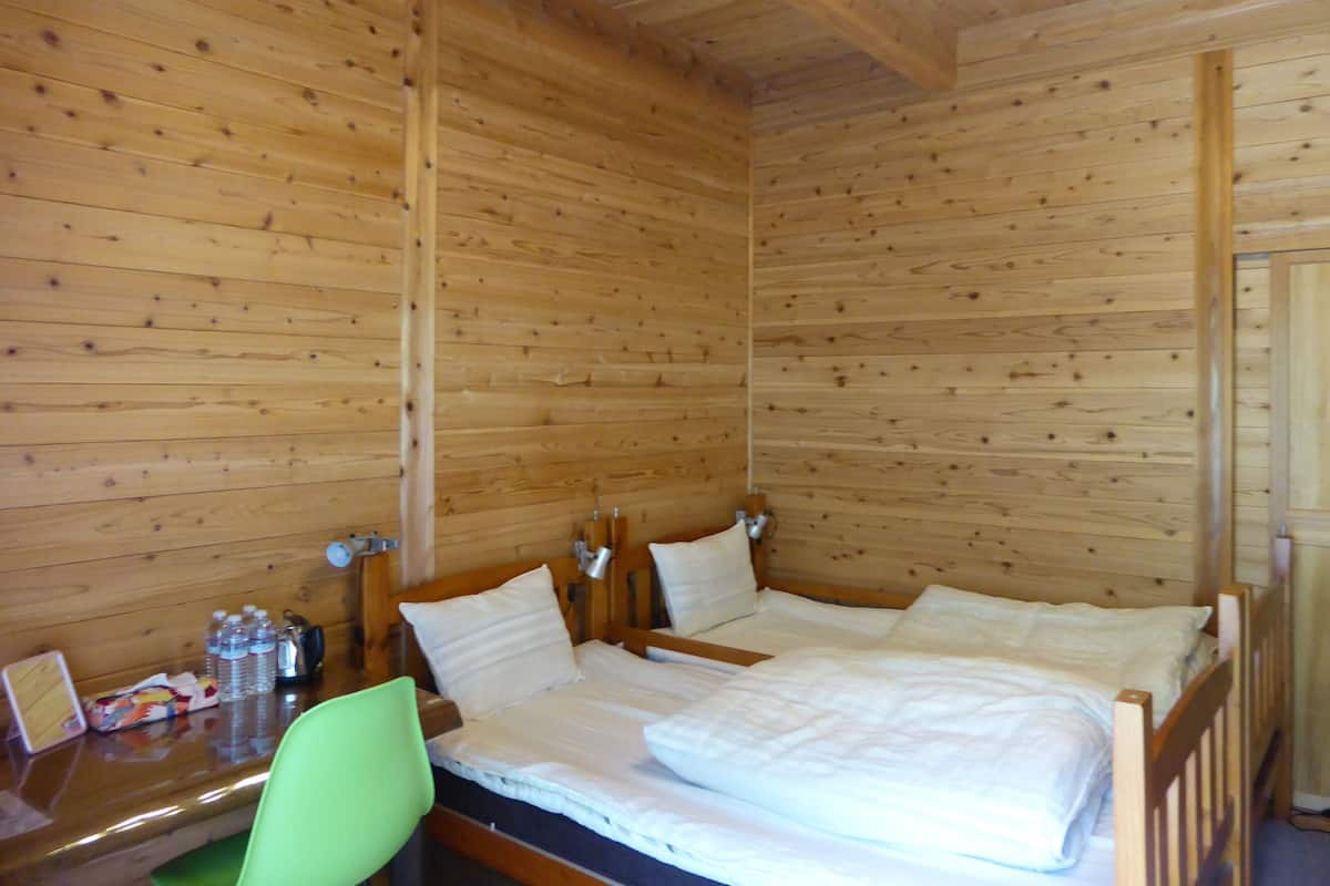 A wooden-paneled room with a bed, a desk, and a chair.