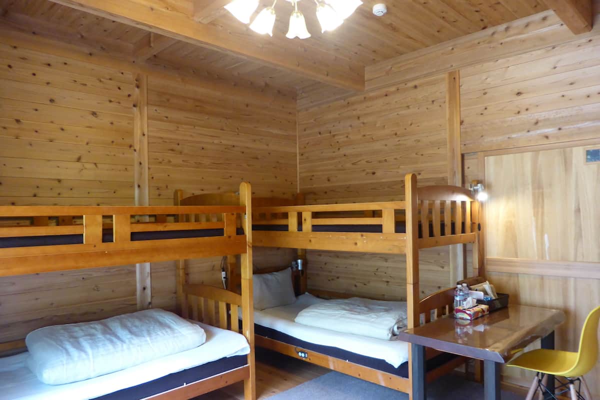 A wooden cabin room with bunk beds, a small table, and a chair.